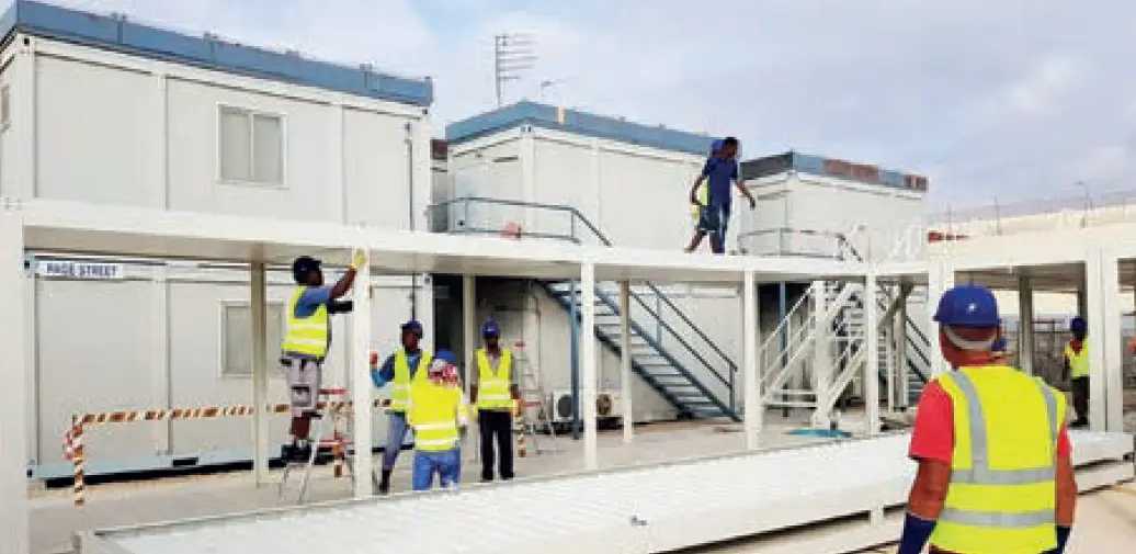 Pramo Prefabrik ekibi, askeri konteyner yaşam alanlarının montajını sahada gerçekleştiriyor; iki katlı modüler yapılar ve çelik bağlantı sistemleri görülüyor.