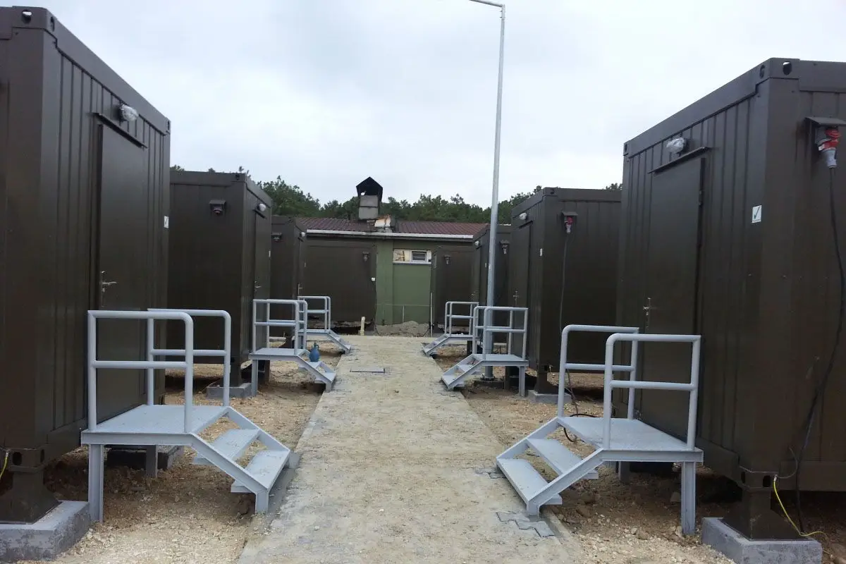Askeri kamp, üs bölgesi veya şantiye için tasarlanmış, her birinin girişi ayrı merdivenli olan askeri yeşil prefabrik konteyner yaşam üniteleri.