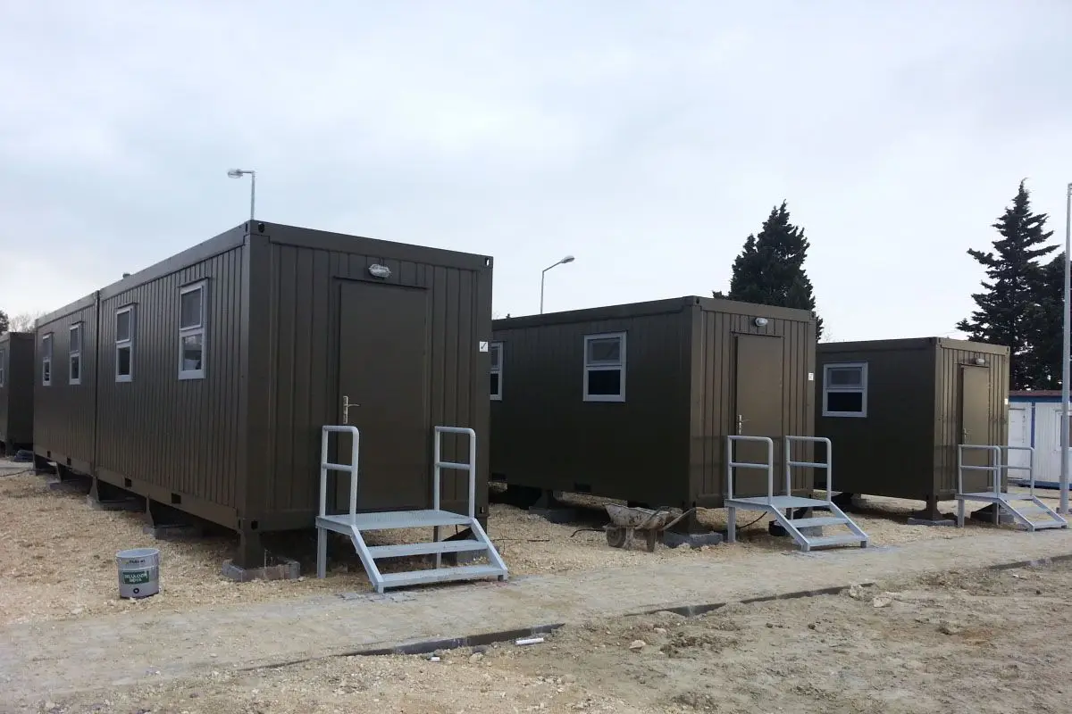 Pramo Prefabrik tarafından üretilen yeşil renkli askeri konteyner yaşam alanları, sahada kuruluma hazır modüler yapılar olarak dizilmiş halde görülüyor.