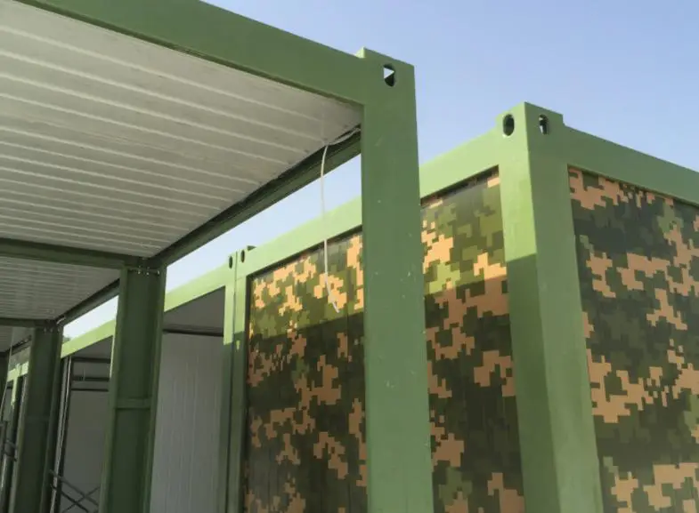Pramo Prefabrik askeri konteyner modülü, yeşil çelik iskelet ve kamuflaj desenli panel kaplamasıyla saha kurulum aşamasında görülüyor.